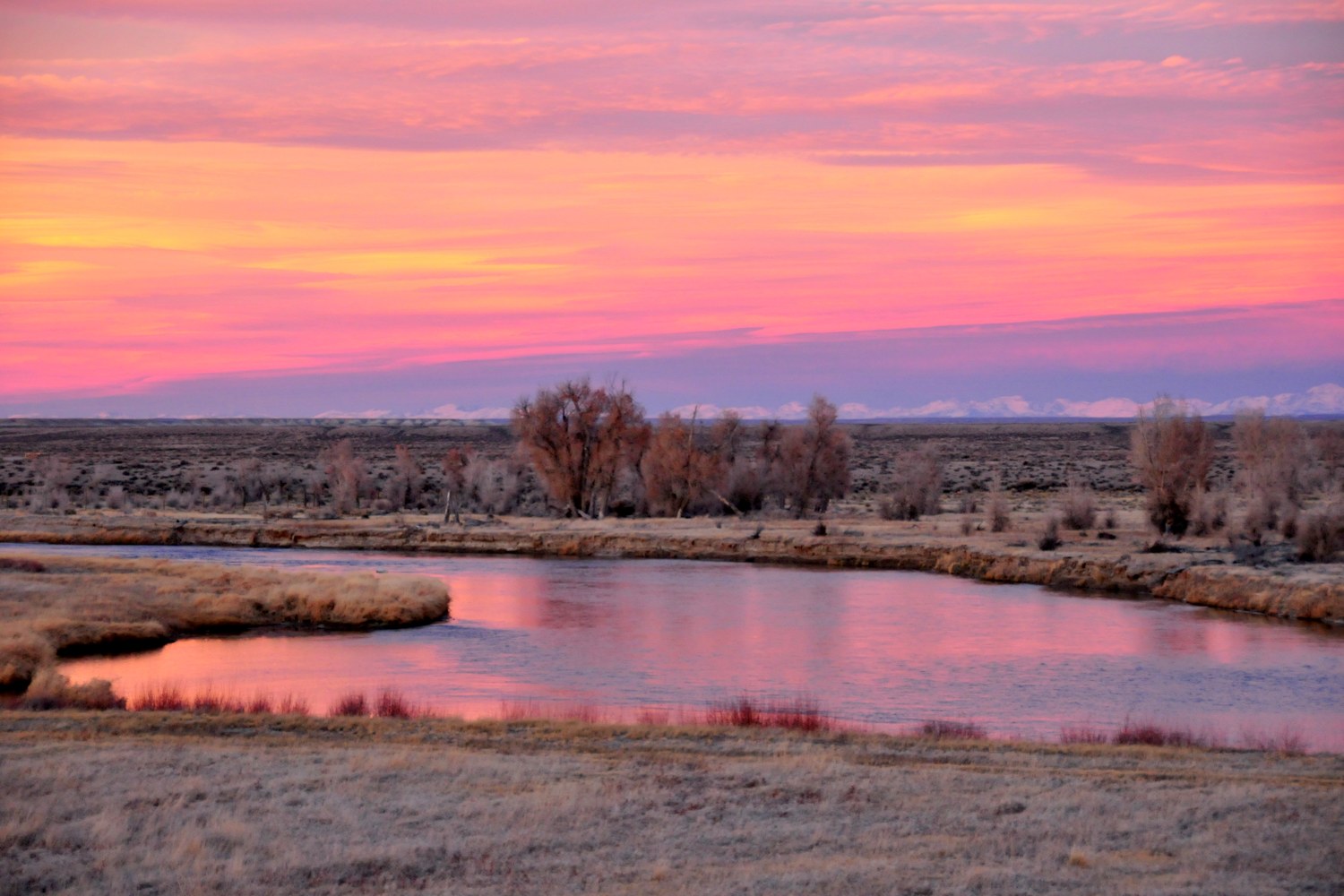 A pink and orange sunset reflected in the Green River as it winds through the Seedskadee refuge.